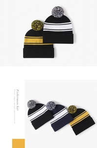 Detail of knitted beanie with pompom showing striped patterns and elastic texture