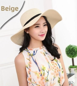 Close-up of a wide-brim beige straw sun hat with minimalist black ribbon detail