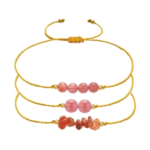 Detailed view of handmade woven bracelets with pink beads and orange stone fragments