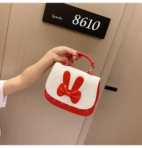 Detail of cute red and white kids handbag featuring 3D rabbit ears and a bow decoration