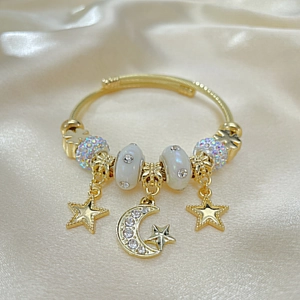 Detail of gold-plated wire bracelet featuring celestial star moon charms and beads