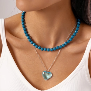 Close-up of double-layered beaded necklace with blue beads and heart-shaped pendant