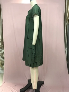 Detail view of dark green V-neck dress with black abstract geometric line patterns