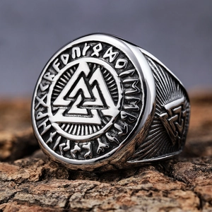 Vintage stainless steel Viking Valknut ring with Norse runes on a rustic wood background
