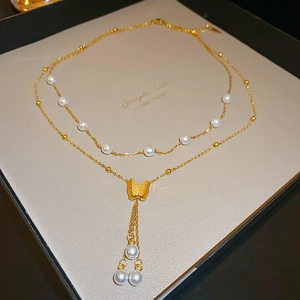 Dettaglio collana a strati con farfalla dorata e perle in scatola regalo
