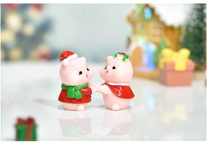 Close-up of adorable resin Christmas pig figurines with festive hats and scarves