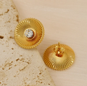 Detailed view of gold titanium earrings featuring radial texture and clear zircon stone
