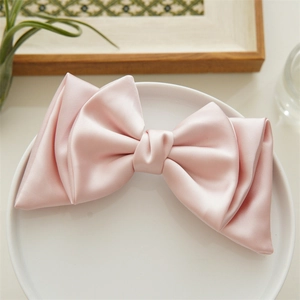 Detailed view of the smooth pink satin bow hair clip texture on a white decorative plate
