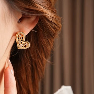 Close-up of gold plated heart-shaped woven earrings with sparkling cubic zirconia on model
