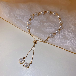 Elegant adjustable pearl bracelet with gold metallic beads on lace background