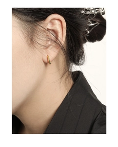 Close-up of minimalist gold geometric hoop earrings on a model with S925 silver texture