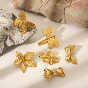 Goldene Edelstahl-Haarklammern mit Libellen und Schleifen auf Naturstein-Dekor