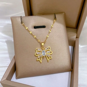 Elegant gold titanium steel hollow bow necklace with crystals on a jewelry pillow