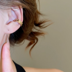 Close-up of triple-layered gold cuff earring worn on ear without piercings