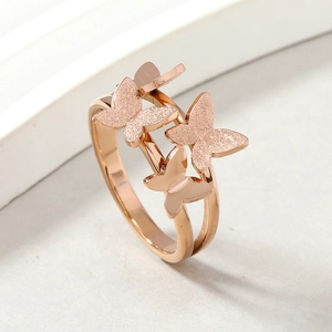 Rose gold stainless steel butterfly ring with frosted and polished textures on white stand