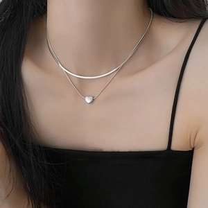Close-up of a silver double-layer snake chain necklace with a heart pendant on a model