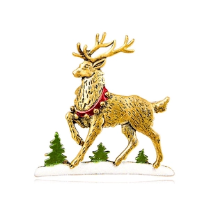 Christmas reindeer brooch with golden antlers and red collar standing on snowy ground