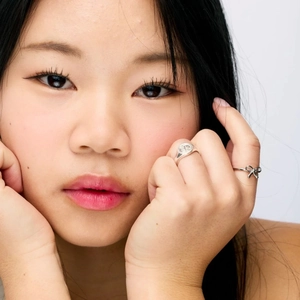 Close-up of elegant bow-knot and round signet silver rings on model hand