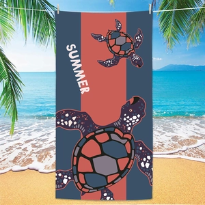 Detail of sea turtle print beach towel hanging by the ocean with Summer text