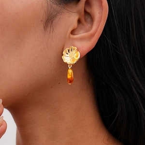 Close-up of elegant flower earrings with amber resin teardrop pendants worn by model