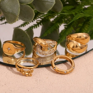 Set of five 18K gold plated stainless steel rings with floral and star motifs on a mirror