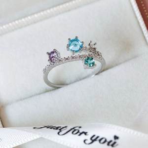 Macro shot of silver heart ring with colorful zircon gems in a luxury gift box