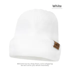 Close-up of white ribbed knit beanie with brown leather outdoor mountain patch detail