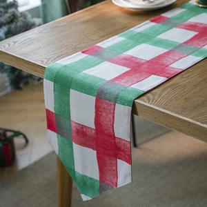 Christmas red and green plaid table runner on wooden table with festive holiday background