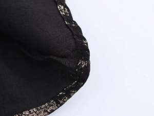 Detailed view of black fabric featuring elegant gold foil texture and reinforced stitching