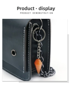 Detail showing orange hexagonal crystal pendant on black leather bag with metal chain