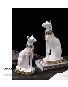 Dettaglio di due statue di gatti egizi Bastet bianchi con collari dorati su legno scuro