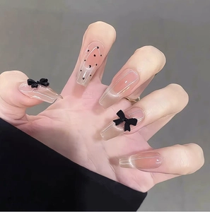 Close-up of long ballerina press-on nails with black bows and polka dots design