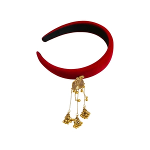Ethnic red velvet headband with a golden bell tassel pendant on a white background