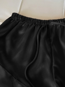 Detail der schwarzen Seidensatin-Schlafanzughose mit elastischem Kordelzug am Taillenbund