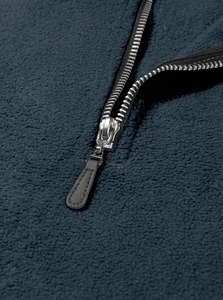Macro detail of navy blue fleece fabric texture and silver metal half-zipper closure