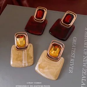 Vintage geometric tortoiseshell resin earrings with gold trim on dark background