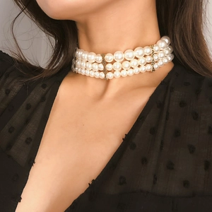 Close-up of elegant triple-layer pearl choker with gold metal accents on model neck