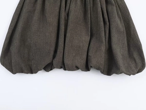 Detail of gathered bubble hem on charcoal cotton dress showing pleated texture