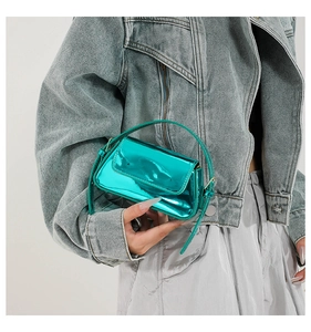 Close-up of a mini bright green metallic handbag held by a model in denim
