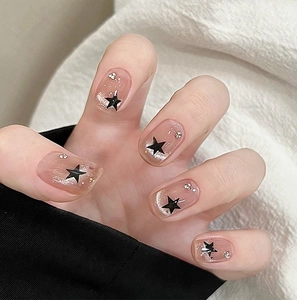 Close-up of pink cat-eye press-on nails with silver glitter and black star accents