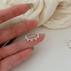 Detailed close-up of 925 silver star ring with black heart stones on a woven texture