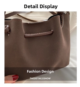 Close-up of brown suede bag showing fine stitching and drawstring closure details