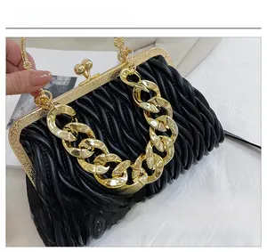 Detailed macro view of vintage black pleated leather bag with gold floral clasp and chain