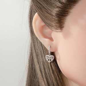 Silver hollow heart earrings with crystal accents worn by a model in a professional close-up