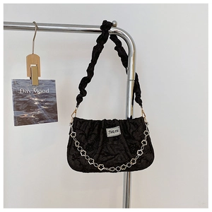Detail of black pleated shoulder bag featuring floral silver chain and textured fabric