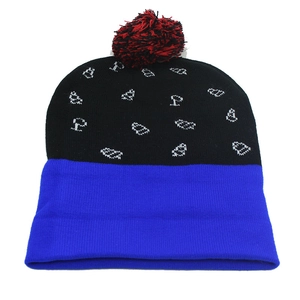 Close-up of a blue and black knit Christmas hat with a red pompom and white patterns