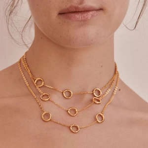 Detailed view of triple-layered gold-plated chain necklace with round pendants on model
