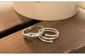Macro detail of S925 sterling silver bamboo knot ring and engraved band on dark wood