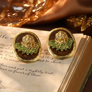 Macro view of vintage oval earrings with golden angel relief and emerald green enamel details