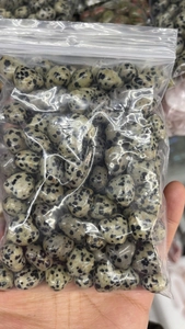 Macro view of 15mm heart-shaped Dalmatian Jasper stones packed in a clear polybag